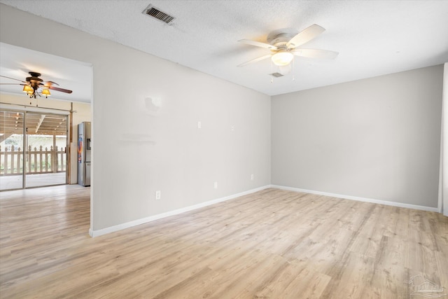 spare room with ceiling fan, light hardwood / wood-style floors, and a textured ceiling