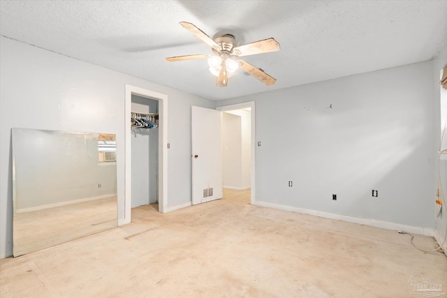 unfurnished bedroom with ceiling fan, light colored carpet, a textured ceiling, and a spacious closet