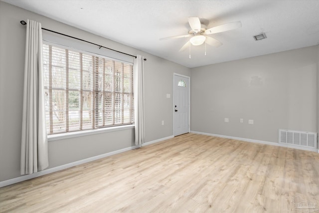 unfurnished room featuring ceiling fan, a healthy amount of sunlight, a textured ceiling, and light hardwood / wood-style floors