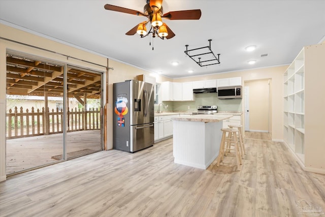 kitchen with white cabinetry, light hardwood / wood-style floors, a breakfast bar area, a kitchen island, and appliances with stainless steel finishes