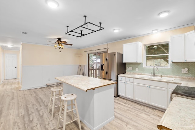 kitchen featuring white cabinets, stainless steel fridge, sink, and a kitchen island