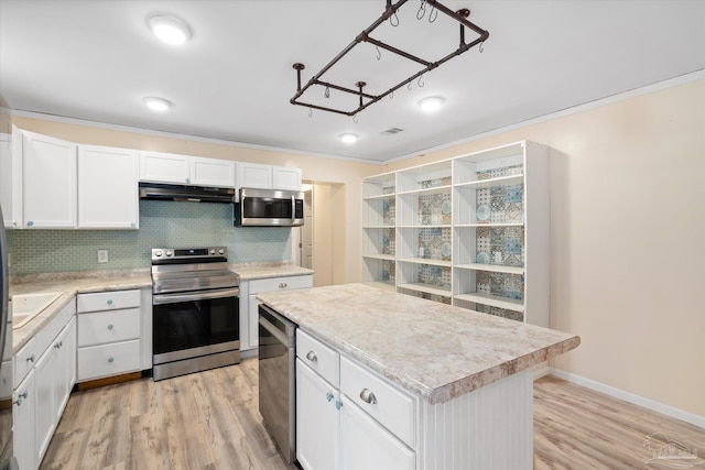 kitchen with light wood-type flooring, backsplash, stainless steel appliances, a kitchen island, and white cabinetry