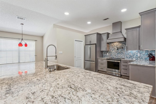 kitchen featuring appliances with stainless steel finishes, decorative light fixtures, sink, backsplash, and custom exhaust hood