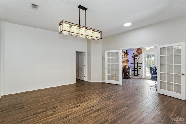 spare room with a textured ceiling, dark hardwood / wood-style flooring, and french doors