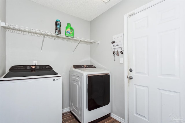 laundry room featuring dark hardwood / wood-style flooring, washing machine and dryer, and a textured ceiling