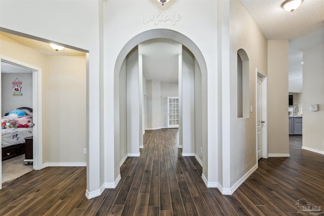 hall with dark hardwood / wood-style flooring, sink, and a textured ceiling