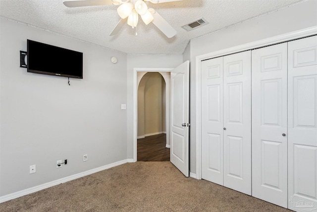 unfurnished bedroom featuring ceiling fan, a closet, a textured ceiling, and carpet