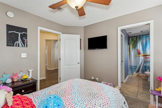 bedroom featuring ceiling fan, connected bathroom, and a textured ceiling