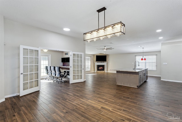 kitchen featuring pendant lighting, sink, french doors, and a center island with sink