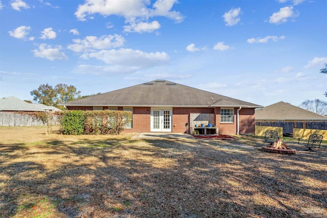 rear view of property featuring a yard, french doors, and an outdoor fire pit