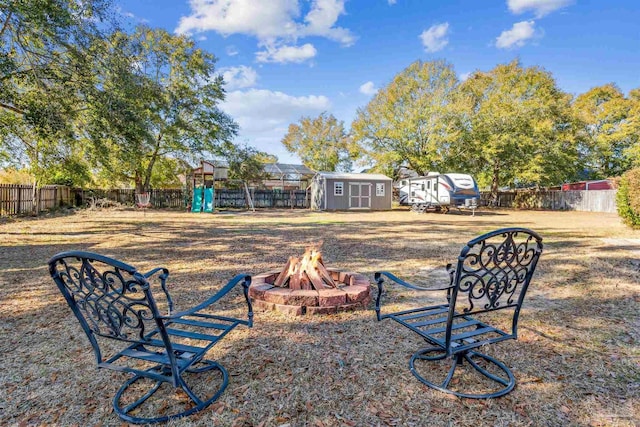 view of yard with a storage shed, an outdoor fire pit, and a playground