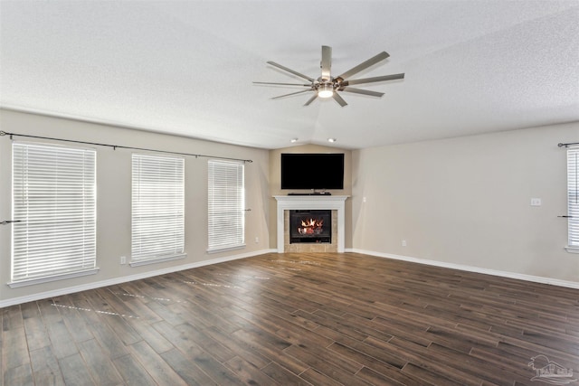 unfurnished living room featuring dark wood-type flooring, vaulted ceiling, a textured ceiling, ceiling fan, and a fireplace