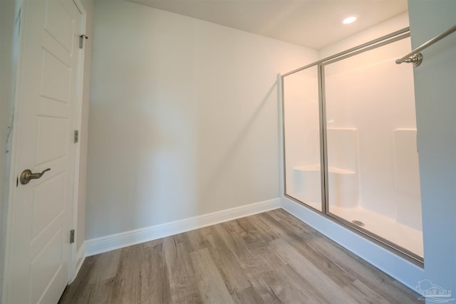 bathroom featuring a shower stall, baseboards, wood finished floors, and recessed lighting