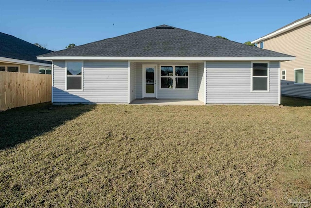 rear view of property with a shingled roof, a patio area, a lawn, and fence