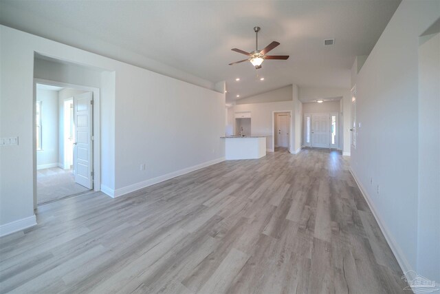 living area with light wood finished floors, visible vents, vaulted ceiling, ceiling fan, and baseboards