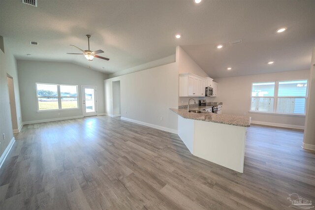 living area with light wood-style floors, visible vents, vaulted ceiling, and a ceiling fan