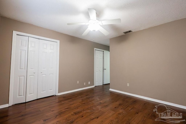 unfurnished bedroom with ceiling fan, dark hardwood / wood-style flooring, and two closets