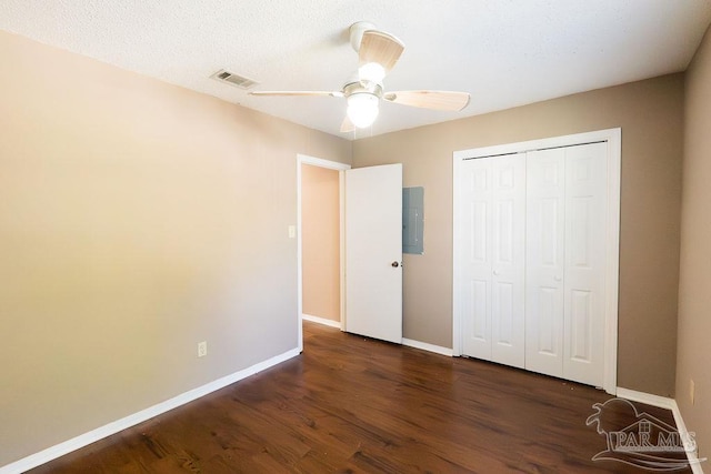 unfurnished bedroom with a closet, electric panel, dark hardwood / wood-style floors, and ceiling fan