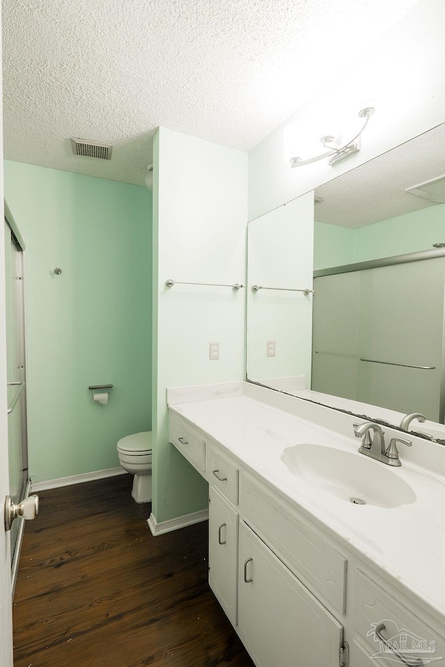 bathroom featuring hardwood / wood-style floors, vanity, an enclosed shower, a textured ceiling, and toilet