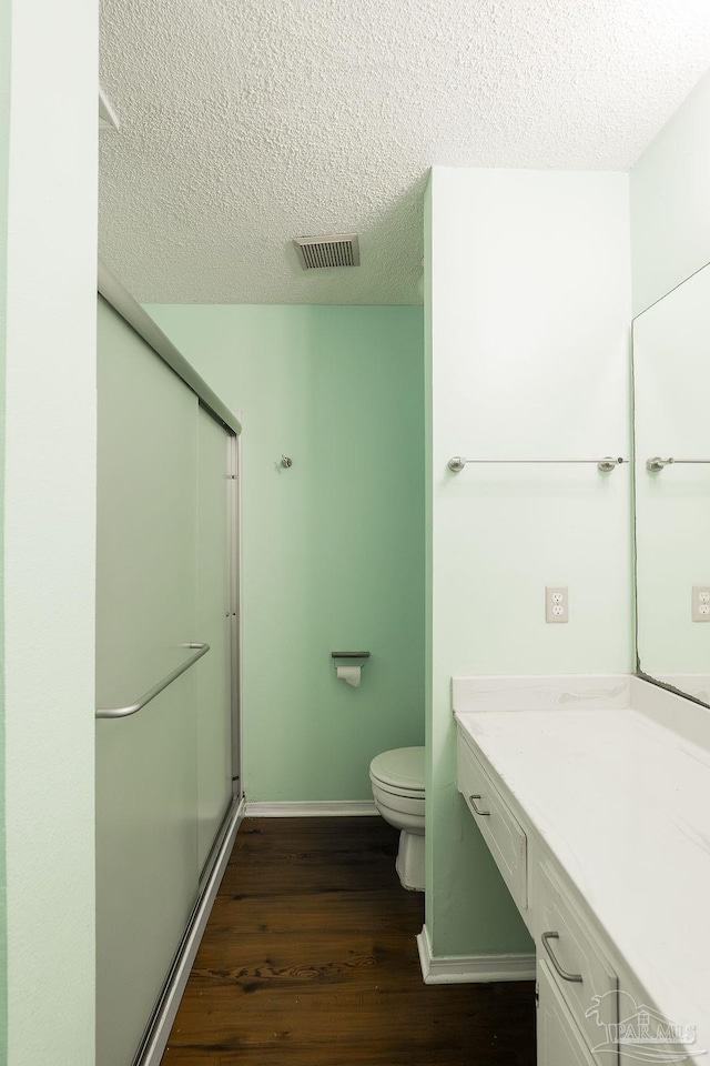 bathroom with hardwood / wood-style flooring, vanity, a textured ceiling, and a shower with shower door