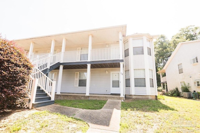 view of front of property featuring a front lawn, cooling unit, and a balcony