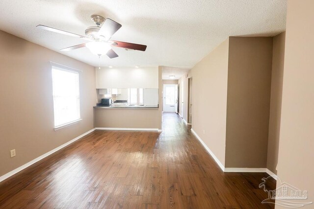 unfurnished living room with hardwood / wood-style flooring, ceiling fan, and a textured ceiling