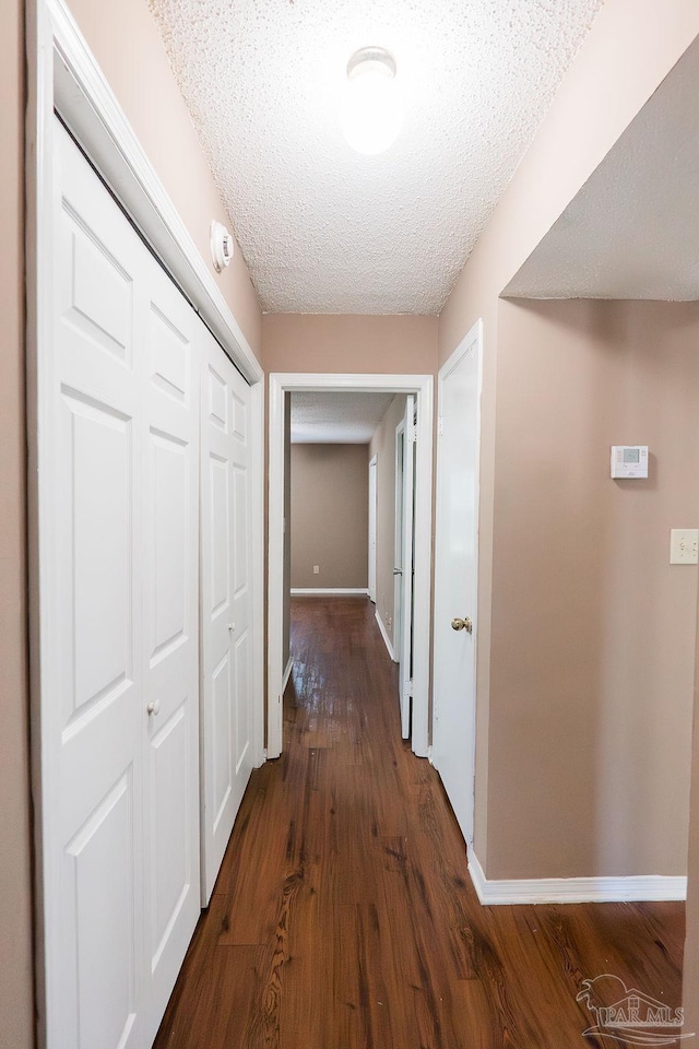 hallway featuring dark hardwood / wood-style floors and a textured ceiling