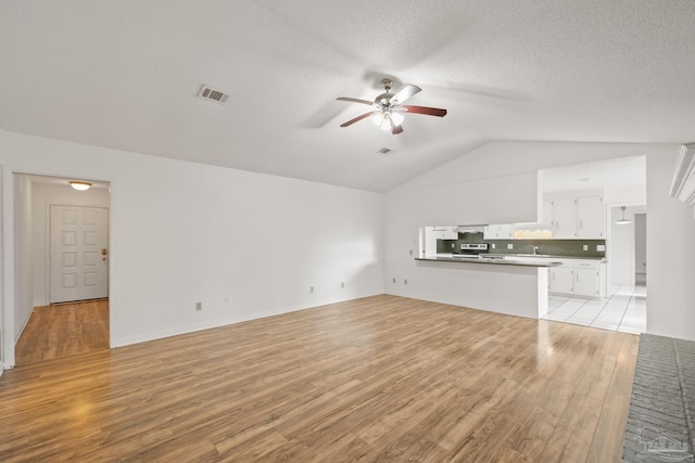 unfurnished living room featuring ceiling fan, vaulted ceiling, and light hardwood / wood-style flooring