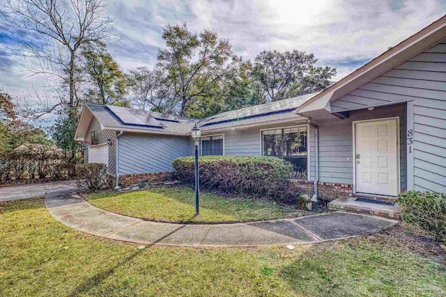 view of front of home with a garage, a front yard, and solar panels