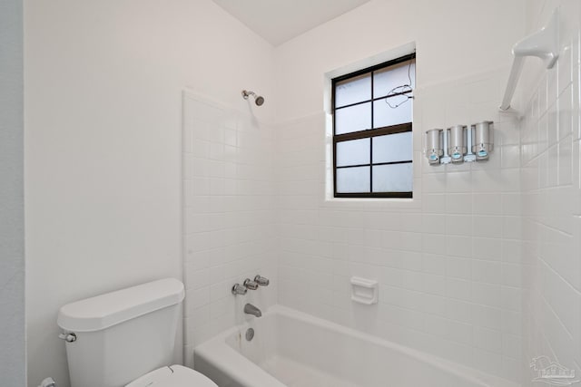 bathroom with tiled shower / bath combo and toilet