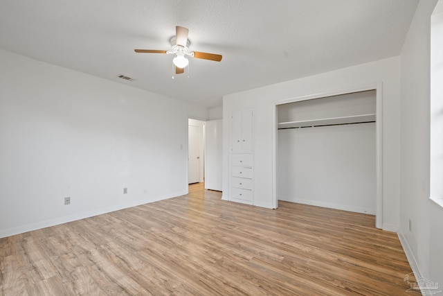 unfurnished bedroom with ceiling fan, a textured ceiling, light hardwood / wood-style floors, and a closet