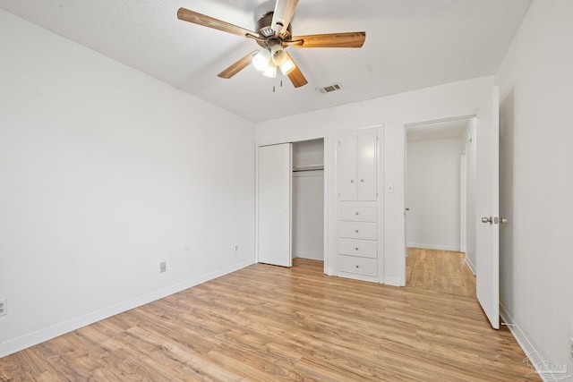 unfurnished bedroom featuring ceiling fan, a closet, light hardwood / wood-style flooring, and a textured ceiling