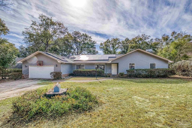 ranch-style home with a garage, a front yard, and solar panels