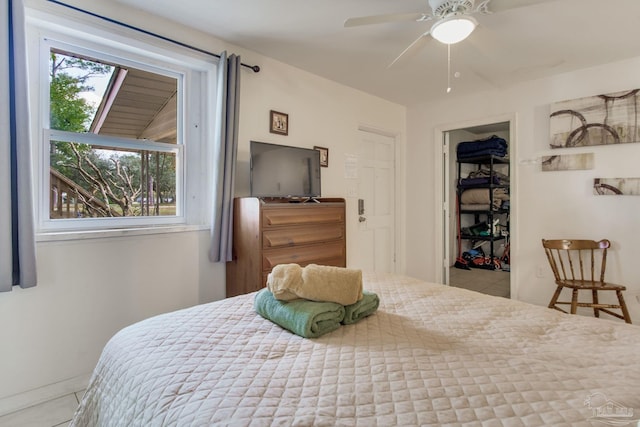 bedroom featuring a walk in closet, a closet, tile patterned flooring, and ceiling fan