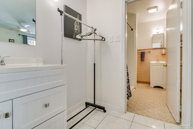 bathroom with curtained shower, tile patterned flooring, vanity, tile walls, and a ceiling fan