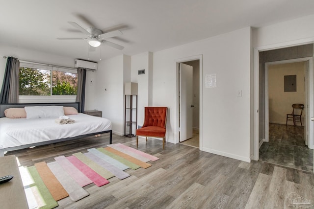 bedroom with electric panel, baseboards, ceiling fan, wood finished floors, and a wall mounted AC