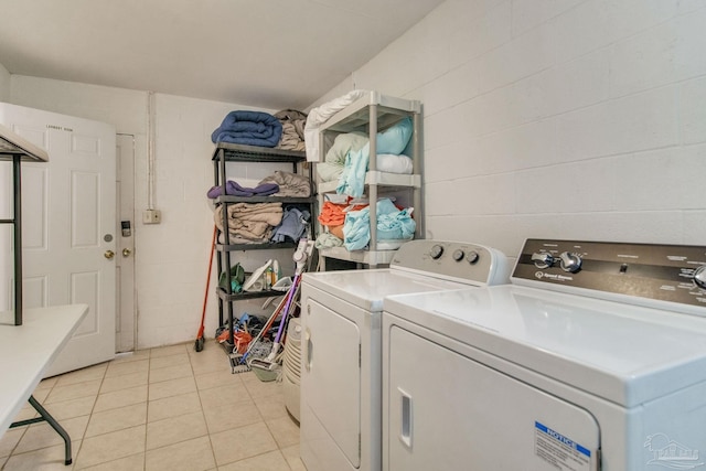 washroom featuring concrete block wall, laundry area, light tile patterned floors, and separate washer and dryer