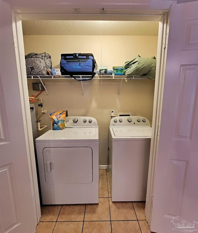 laundry room with washer and dryer, laundry area, a textured ceiling, and light tile patterned flooring