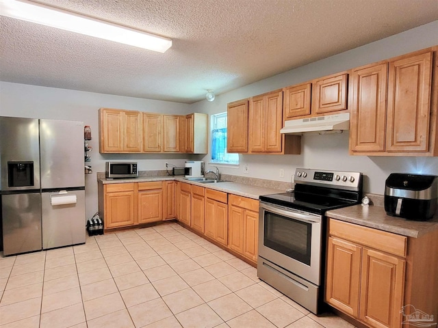 kitchen with stainless steel appliances, under cabinet range hood, a textured ceiling, and light tile patterned flooring