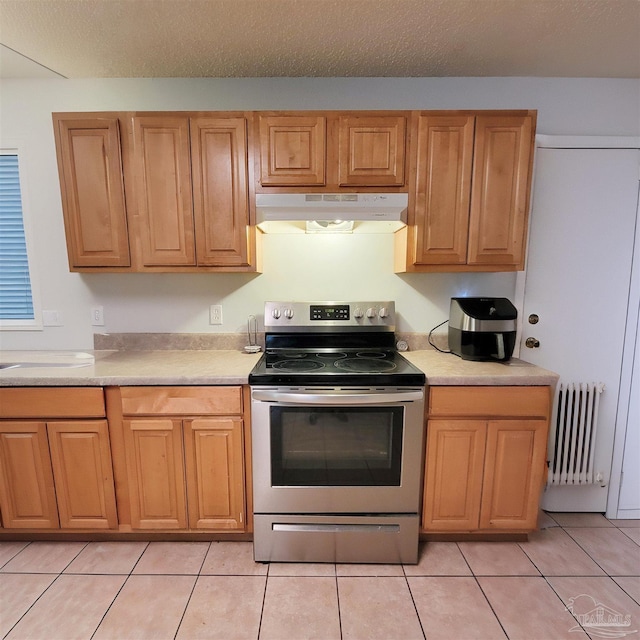 kitchen with stainless steel electric range, under cabinet range hood, light countertops, and radiator