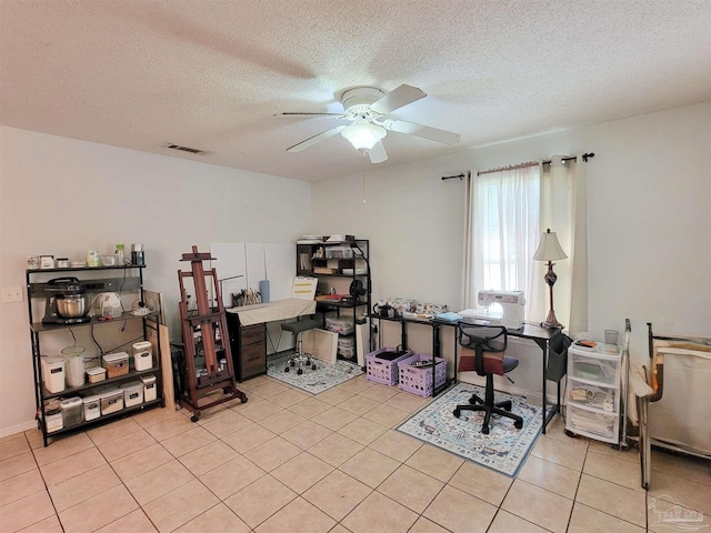 home office featuring light tile patterned floors, visible vents, a textured ceiling, and ceiling fan
