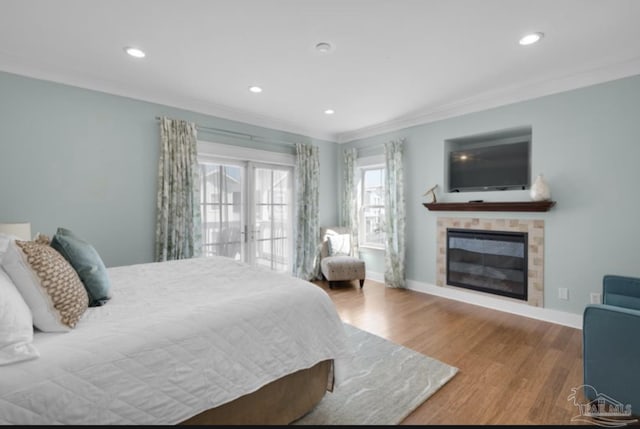 bedroom featuring wood-type flooring, ornamental molding, and a tile fireplace