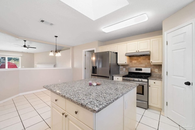 kitchen with under cabinet range hood, stainless steel appliances, visible vents, a center island, and tasteful backsplash