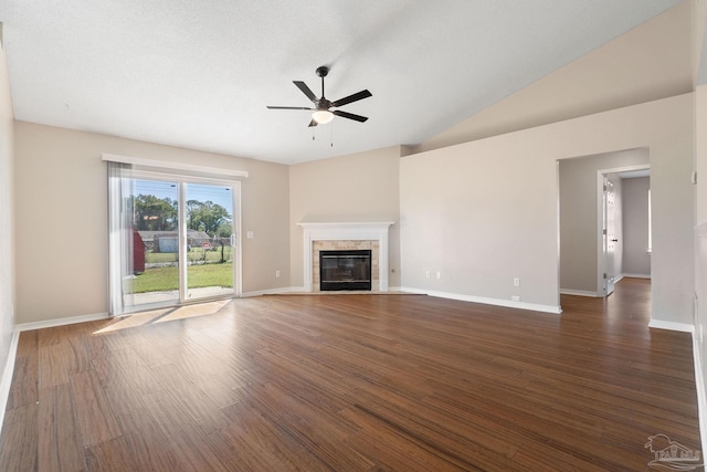 unfurnished living room featuring lofted ceiling, a tiled fireplace, dark wood-type flooring, a ceiling fan, and baseboards