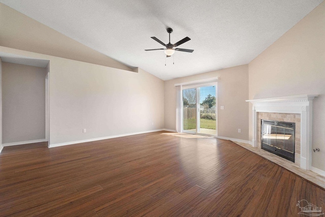 unfurnished living room featuring lofted ceiling, a fireplace, wood finished floors, a ceiling fan, and baseboards