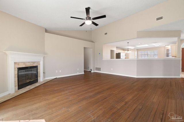 unfurnished living room featuring lofted ceiling, visible vents, a tiled fireplace, and wood finished floors