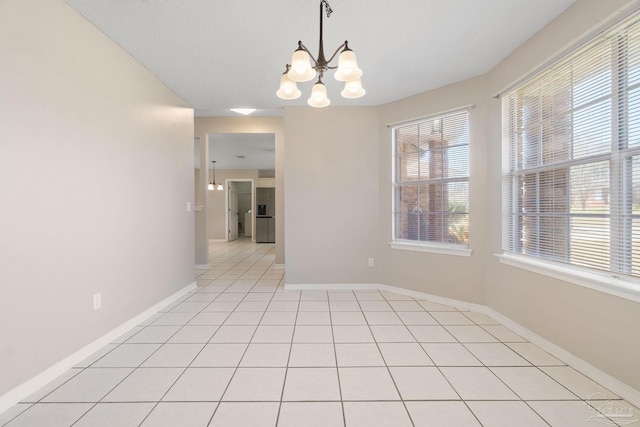 unfurnished room featuring light tile patterned floors, plenty of natural light, baseboards, and an inviting chandelier