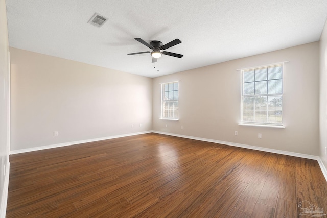 unfurnished room featuring dark wood-type flooring, visible vents, a textured ceiling, and baseboards