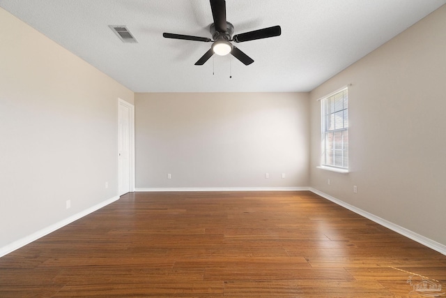 unfurnished room featuring ceiling fan, wood finished floors, visible vents, and baseboards