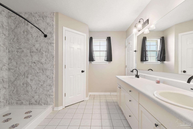 full bathroom featuring double vanity, a shower stall, a textured ceiling, and a sink